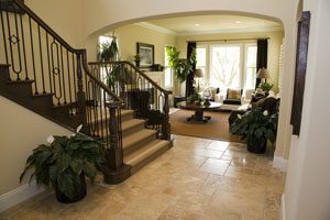 A clean tile floor leading into a living room with a staircase
