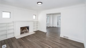 An empty room with wood flooring and a white fireplace
